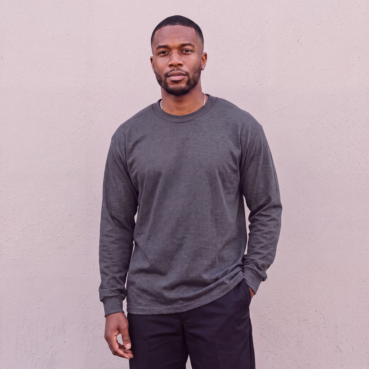 Model wearing Pro Club Men's Heavyweight Cotton Long Sleeve Crew Neck T-Shirt in Charcoal