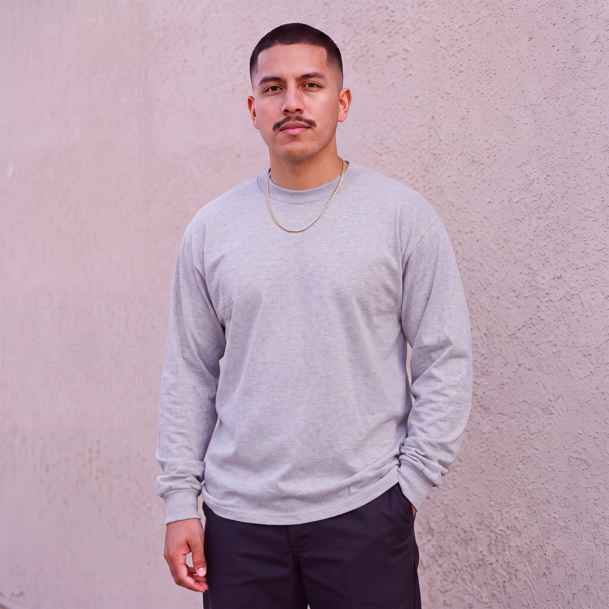 Model wearing Pro Club Men's Heavyweight Cotton Long Sleeve Crew Neck T-Shirt in Heather Grey