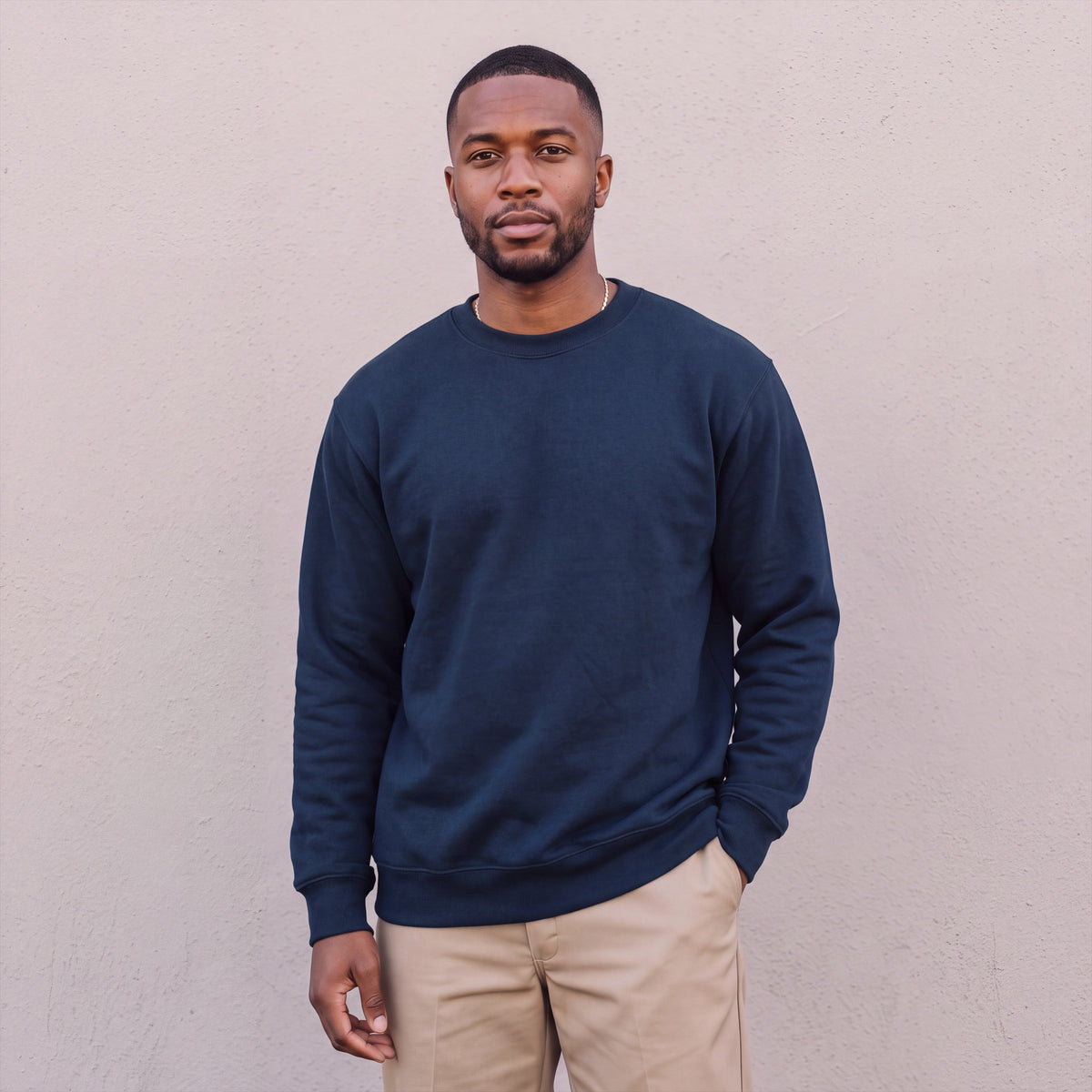 Model wearing Pro Club Men's Heavyweight Crew Neck Fleece Pullover Sweater (13oz) in Navy