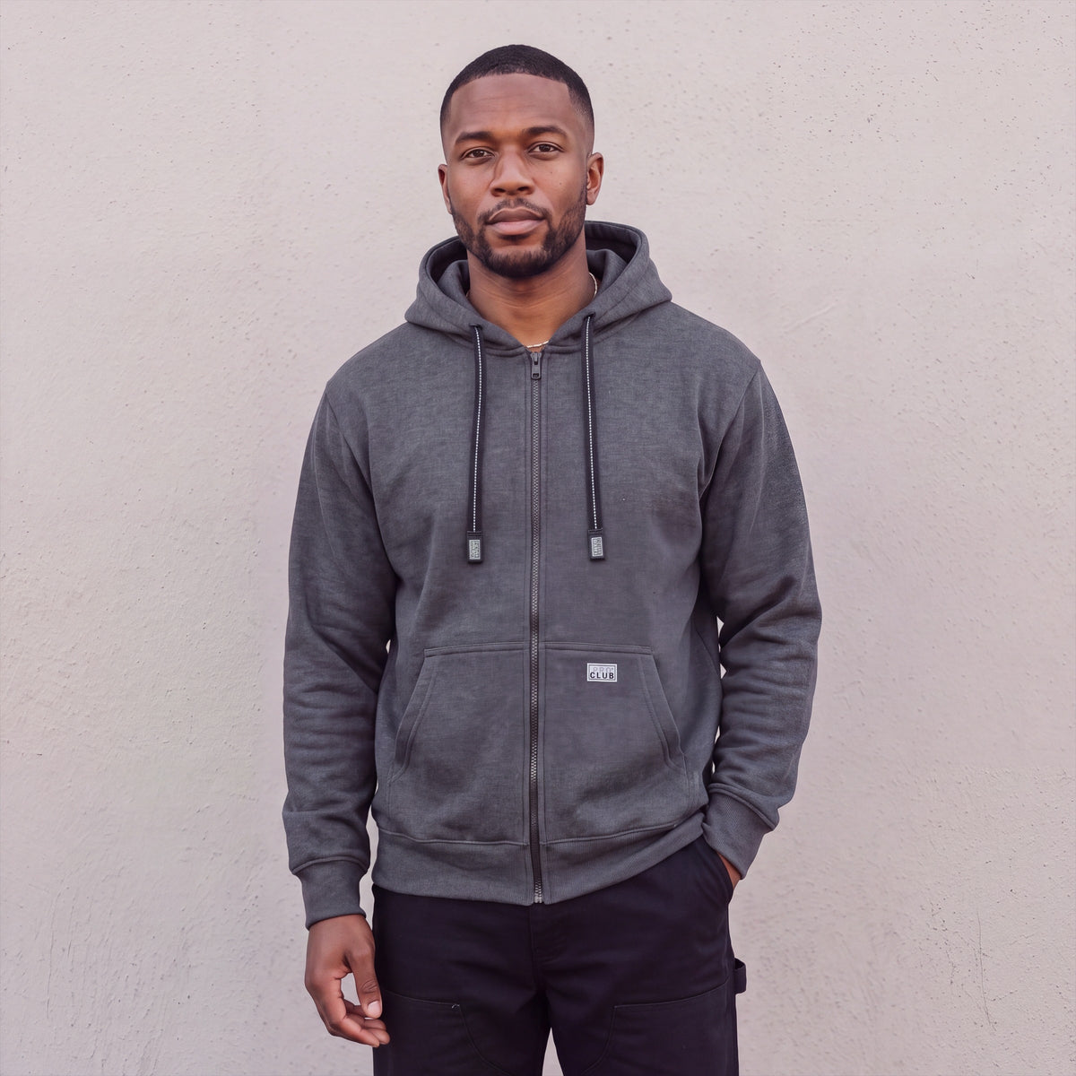 Model wearing Pro Club Men's Heavyweight Full Zip Fleece Hoodie in Charcoal